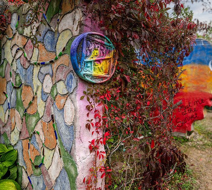 Colorful mosaic wall and garden art along a creative outdoor pathway.