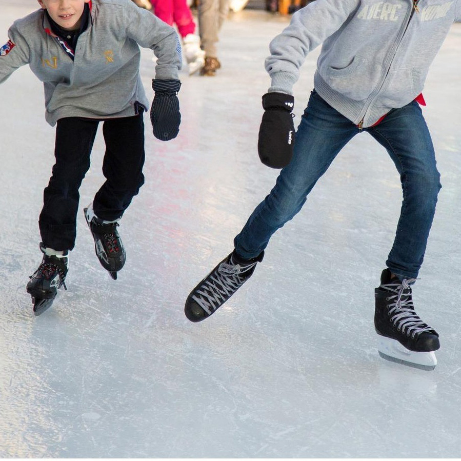 Two young boys are skating on ice.
