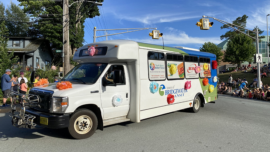 Bridgewater Transit bus decorated for a parade driving through downtown with spectators along the street