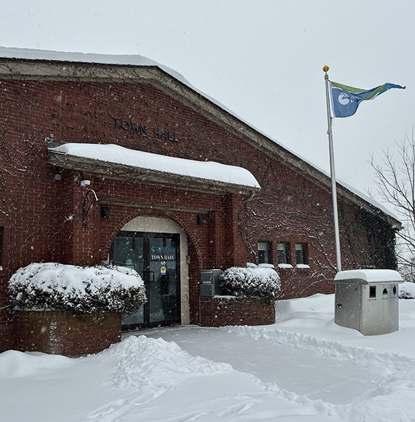Bridgewater Town Hall during a winter snowfall with the town flag flying outside the building.